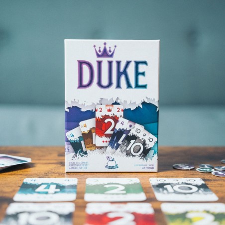 Gros plan sur les cartes et la boîte de DUKE, mettant en avant le matériel et les illustrations du jeu.